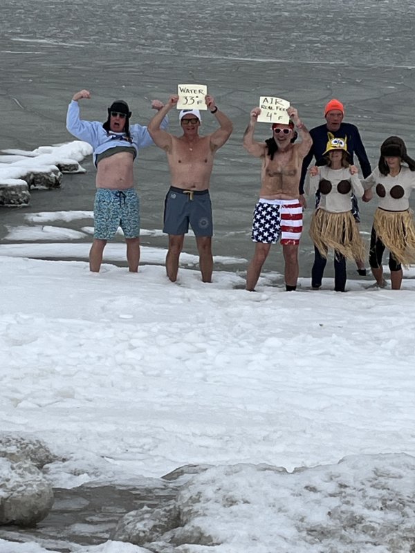 Braving the Lewes Beach tundra Jan. 31 to display the air and water temperature signs for their plunge are (l-r) Chip Simpson, Rob Coupe, Bob Pierce, Ken Tadler, Andrea Sutton and Bo Lee. For the record, the water temp was a barely-above-freezing 33, and the “real feel” air temperature was 4.